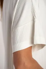 Remera de corte oversize, color blanco, confeccionada en tejido acanalado con mangas cortas y cuello redondo.