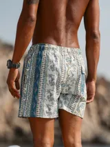 Short de baño con estampado ornamental de estilo paisley y rayas verticales en tonos azules, verdes y blancos. Cuenta con cintura elástica, dos bolsillos laterales y un bolsillo trasero.