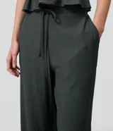 Pantalón palazzo de viscosa texturizada, color verde oscuro, de tiro alto con cintura elastizada, lazo frontal regulable y bolsillos laterales.