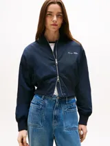 Campera tipo bomber de corte cropped y calce amplio en color azul marino. Cuenta con acabado repelente al agua, aislamiento térmico y relleno ligero. Presenta cuello estilo béisbol, cierre frontal de cremallera, dos bolsillos delanteros ribeteados y terminaciones en punto canalé en cuello, puños y bajo. Incluye el logo de Tommy Hilfiger bordado en el pecho.