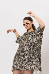 Camisa de corte oversize, con diseño estampado animal print de cebra, mangas cortas amplias y cierre frontal con botones.
