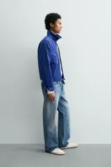 Sobrecamisa regular fit de Zara, confeccionada en pana de algodón color azul con efecto lavado. Cuenta con cuello solapa, manga larga con puño y botón a presión, bolsillos frontales de plastrón con solapa y cierre de cremallera.