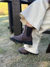 Bota tipo Chelsea de cuero color chocolate, con paneles elásticos laterales y suela track dentada de goma negra.