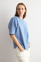 Camisa de manga corta a rayas azules y blancas, con cuello mao y cierre frontal oculto.