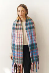 Bufanda larga con estampado a cuadros en tonos celeste, azul, rojo, verde y blanco. Incluye flecos multicolores en los extremos.