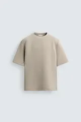 Sudadera de manga corta con cuello redondo, confeccionada en tejido técnico de algodón con elasticidad. Presenta un corte relajado y una aplicación de tacha metálica en la espalda.