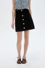 Minifalda de jean blanca de corte recto, con botonera frontal con botones metálicos dorados y costuras pespunteadas a contratono.