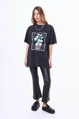 Remera de algodón con efecto acid wash en color negro, de corte oversize y manga corta. Presenta un estampado frontal enmarcado que ilustra un jarrón con flores blancas.