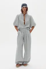 Pantalón de lino de corte ancho con diseño a rayas, tiro alto, bolsillos laterales y pinzas frontales.