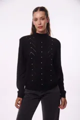 Sweater negro de tejido de punto con cuello alto y mangas largas. Presenta calados en forma de rombos y apliques de strass.