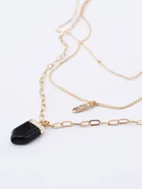 Collar de tres niveles en tono dorado, con cadenas de diferentes diseños, un dije pequeño con piedra brillante y un dije central en forma de punta de piedra negra.
