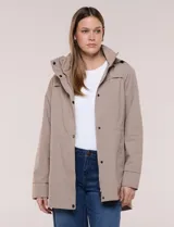 Campera impermeable Gallery de color beige, con capucha plegable, cierre frontal oculto con botones a presión, bolsillos delanteros y cordón de ajuste en la cintura.