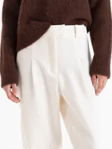 Pantalon negro de corte tipo babucha, con cintura estructurada, presillas para cinturón, bolsillos traseros y ruedos ajustados con puños tejidos.