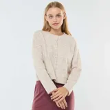 Chaqueta color beige de tejido de punto, corte cropped, con cuello redondo y cierre frontal con botones.