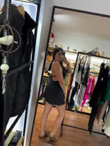 Vestido corto negro con escote halter atado al cuello.