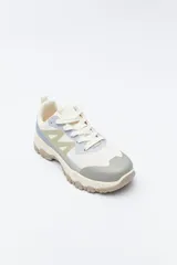 Zapatilla deportiva de inspiración outdoor con diseño de paneles en tonos neutros, que combina malla y materiales sintéticos. Presenta una suela robusta con relieve dentado para mayor tracción y estabilidad.