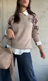 Sweater de punto color beige con cuello redondo y diseño de flores bordadas en tonos oscuros en el frente y las mangas.