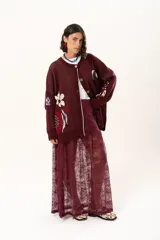 Saco tejido de punto en color bordó, con diseño de granada en la parte frontal y detalles bordados. Presenta cierre frontal con botones, cuello redondo y mangas largas con puños acanalados. El diseño incluye elementos artesanales y bordados a mano en la espalda.