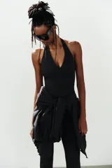 Mono de poliamida color negro con escote halter y escote en V profundo, de corte ajustado y largo por encima de la rodilla.