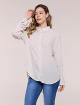 Camisa Magaschoni de silueta holgada y tejido texturizado color blanco, con cuello camisero, cierre frontal de botones, mangas largas con presilla para arremangar y diseño asimétrico con espalda más larga.