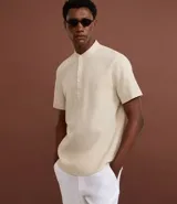 Camisa de manga corta confeccionada en mezcla de lino y algodón, con cuello tipo padre y cierre frontal parcial con botones.