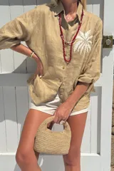 Camisa blanca de lino con bordado de pulpo azul en el pecho, de corte recto y manga larga.