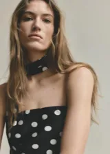 Vestido largo negro con estampado de lunares blancos, diseño asimétrico de un solo hombro y tejido fluido de poliéster. Incluye un fular a juego para el cuello.