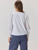 Camisa de color marrón con diseño combinado, presentando mangas abullonadas con volados en los hombros y cuerpo de algodón. Combina una textura de tela de camisa en mangas y delantero con una espalda de tejido elástico.
