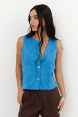 Top azul sin mangas con cuello solapa, cierre frontal de botones y estampado floral bordado.