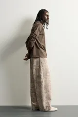 Pantalón relaxed fit de algodón con estampado animal print de cocodrilo en tonos beige y gris. Tiene diseño de cinco bolsillos, cierre frontal con cremallera y botón, y una tira con bolsillo multifunción en la pernera.