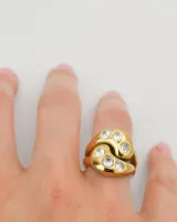 Anillo dorado con forma de yin yang con incrustaciones de circonitas. Fabricado en acero quirúrgico recubierto de oro con tecnología PVD.