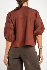 Blusa de viscosa y lino color crudo, con cuello en V, mangas tres cuartos abullonadas e inserciones de encaje floral y detalles plisados frontales.