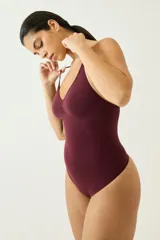 Body tanga modelador color borravino con efecto vientre plano y copas sin aros que realzan el busto. Cuenta con breteles finos ajustables y diseño sin costuras laterales.