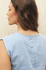 Top sin mangas de lino y viscosa, color negro, con escote redondo y caída relajada. Presenta hombros levemente marcados y botones forrados en la espalda.