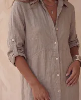 Vestido camisero midi blanco de lino, con cuello camisero, botonadura frontal completa con botones de nácar, mangas largas con tira para arremangar y abertura lateral en el bajo.
