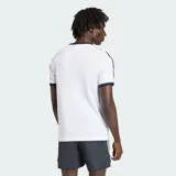 Remera Adidas modelo 3S Ringer de color blanco, con cuello redondo y ribetes en las mangas de color negro. Presenta el logotipo y el texto de la marca estampados en el pecho en color negro, junto con las clásicas tres tiras en los hombros y mangas.