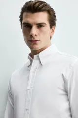 Camisa regular fit de algodón con diseño de rayas finas celestes y blancas. Cuenta con cuello abotonado, manga larga con puños abotonados y cierre frontal de botones.