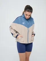 Campera cortaventos Umbro de diseño colorblock en tonos celeste, beige y azul marino, con cuello alto, cierre frontal y bolsillos laterales.