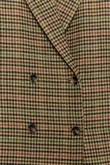 Blazer de corte entallado con estampado de cuadros, cuello solapa y cierre frontal cruzado con botones. Presenta mangas largas con detalle de abertura y botones en los puños, y forro interior a contraste.