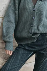 Cardigan de punto color marrón chocolate, de calce relajado, con cierre frontal de botones, mangas amplias y capucha integrada.
