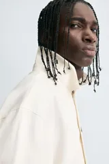 Sobrecamisa negra de algodón con estructura canvas, corte cropped y calce holgado. Presenta cuello solapa, manga larga, bolsillos laterales en cadera y cierre frontal con botones a presión metálicos.