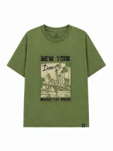 Remera de corte holgado en color verde oliva con efecto lavado. Presenta un estampado gráfico frontal con temática urbana de Nueva York, incluyendo el puente de Manhattan y palmeras.