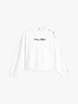 Buzo de felpa blanco de Tommy Hilfiger con cuello redondo, manga larga y calce regular. Cuenta con el logotipo de la marca bordado en tipografía script en el pecho y botones dorados decorativos en el hombro.