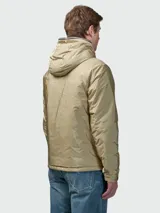 Campera tipo plumífero corto de Moncler, color beige con acabado satinado. Presenta capucha integrada, cierre frontal con cremallera, bolsillos laterales y un bolsillo con solapa en la manga izquierda que incluye el logo de la marca.