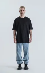Remera de corte relajado y silueta amplia, con hombros levemente caídos y mangas cortas. Confeccionada en algodón premium, presenta un diseño liso y minimalista.