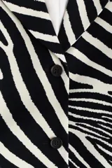 Blazer de botonadura sencilla en sarga de algodón, de ajuste entallado, con solapas de pico, hombreras, bolsillos delanteros con solapa y abertura en los puños.
