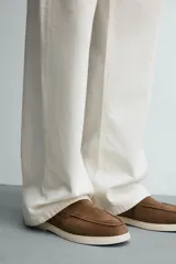 Mocasines casuales para hombre, fabricados en piel con acabado en serraje color marrón, de corte liso con detalle de bordón y suela blanca a contraste.