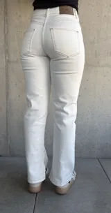 Pantalón de jean color natural, de corte recto con tajos en el lado interno de la pierna y costuras color oro.