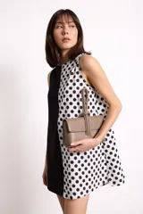 Vestido corto sin mangas con escote recto, confeccionado con paneles combinados: un lado negro liso y el otro blanco con estampado de lunares negros. Posee bolsillos ocultos laterales.