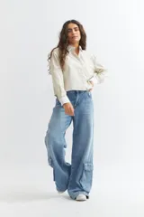 Camisa de manga larga con cuello y puños blancos contrastantes. El cuerpo de la camisa es de color crema con finas rayas verticales azules y tiene un corte crop.